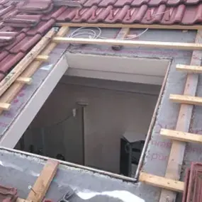 Dach mit roten Ziegeln und Öffnung für Dachfenster, Dachsanierung und Fenstereinbau.