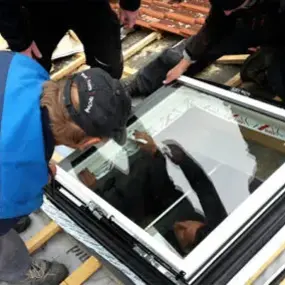 Handwerker montieren ein modernes Dachfenster auf einer Baustelle für energetische Sanierung.