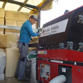 Ein Handwerker bedient eine Einblasmaschine für Zellulosedämmung im Trockenbau.