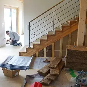 Ein Handwerker installiert Dämmung und Elektroarbeiten im modernen Holzhaus-Neubau.