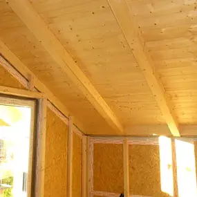 Innenansicht eines Dachgeschosses mit sichtbarer Holzdecke und moderner Dämmung.